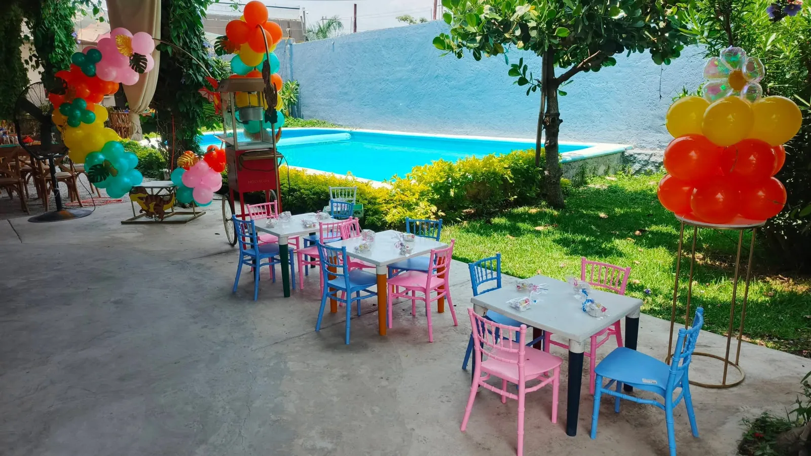 Celebración con mesas coloridas junto a alberca